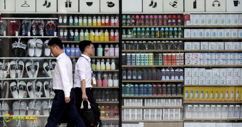 Chinese men walk by a global chain store selling household items in Beijing, Monday, July 31, 2017. (AP Photo/Andy Wong)